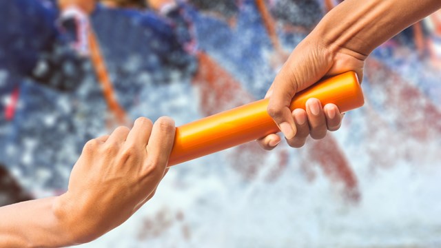 hands passing a relay baton on rowing team background and color tone effect.